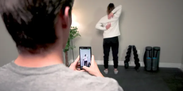 Physical trainer taking workout videos for client.